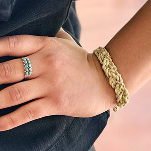detail of woman's hand on her hip showing a small turquoise ring and braided bracelet